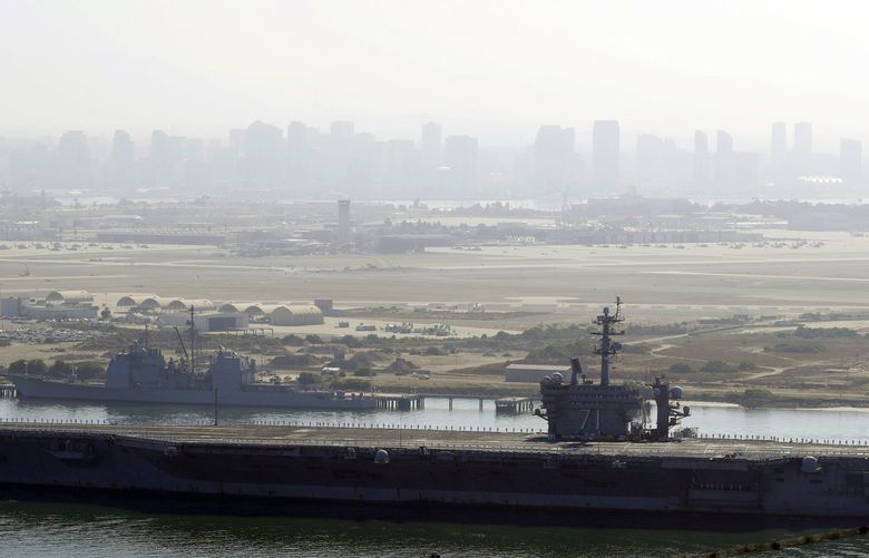 FILE – In this July 9, 2020 file photo the USS Theodore Roosevelt aircraft carrier makes its way into San Diego Bay as seen from San Diego. Three sailors aboard the USS Theodore Roosevelt have tested positive for COVID-19, the Navy said Monday, Feb. 15, 2021, less than a year after a massive outbreak on the ship sidelined it in Guam for nearly two months. (AP Photo/Gregory Bull, File)