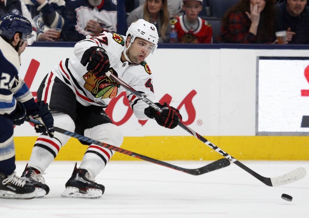 Chicago Blackhawks forward John Quenneville, right, passes the puck in front of Columbus Blue Jackets forward Nathan Gerbe during an NHL hockey game in Columbus, Ohio, Sunday, Dec. 29, 2019. (Paul Vernon / AP)