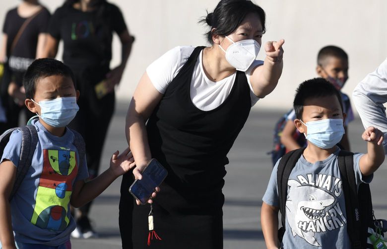 Masked parents direct their children on the first day of school at Enrique S. Camarena Elementary School, Wednesday, July 21, 2021, in Chula Vista, Calif. The school is among the first in the state to start the 2021-22 school year with full-day, in-person learning. (AP Photo/Denis Poroy) CADP111 CADP111