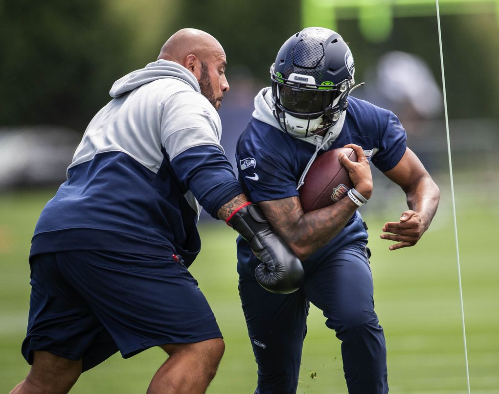 Rashaad Penny runs the boxing drill in which assistant coaches donning boxing gloves provide resistance on the run Wednesday, July 28, 2021 at the VMAC in Renton, WA. (Dean Rutz / The Seattle Times)