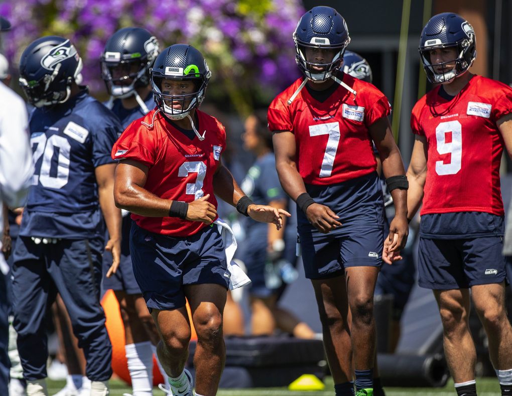 Russell Wilson joins quarterbacks Geno Smith (7) and Danny Etling (9) in warming up for Thursday’s practice. (Dean Rutz / The Seattle Times)