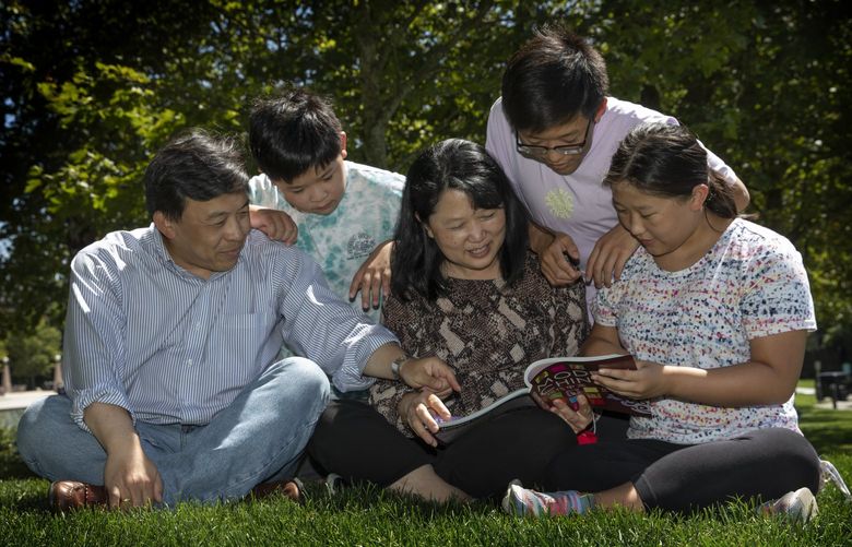 Hazel Li (c)  reads from  a book from her childrenâ€™s Chinese language school as the rest of her family looks on  in Bellevueâ€™s Downtown Park in Bellevue Thursday, July 29, 2021.   L – R â€” Liam Li, Eddy, 9.Hazel, Richard, 14 and Edmunda, 13.  The family talks about the challenges of attending a Chinese language school during the pandemic.

 217761
