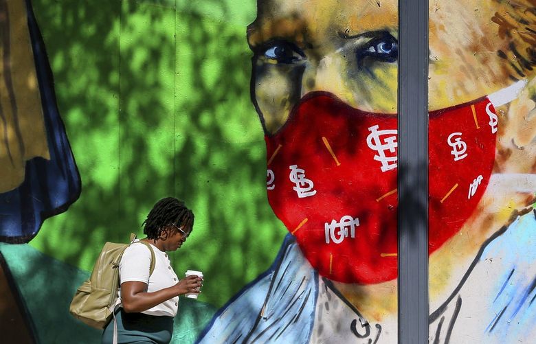 A woman passes a mural seeking to encourage mask wearing on Monday, July 26, 2021, in the 100 block of S. 11th St. in downtown St. Louis. A second mask mandate takes effect in the city and St. Louis County amid a surge of the Delta variant of COVID-19 threatens the health of the unvaccinated. (Christian Gooden/St. Louis Post-Dispatch via AP) MOSTP902 MOSTP902