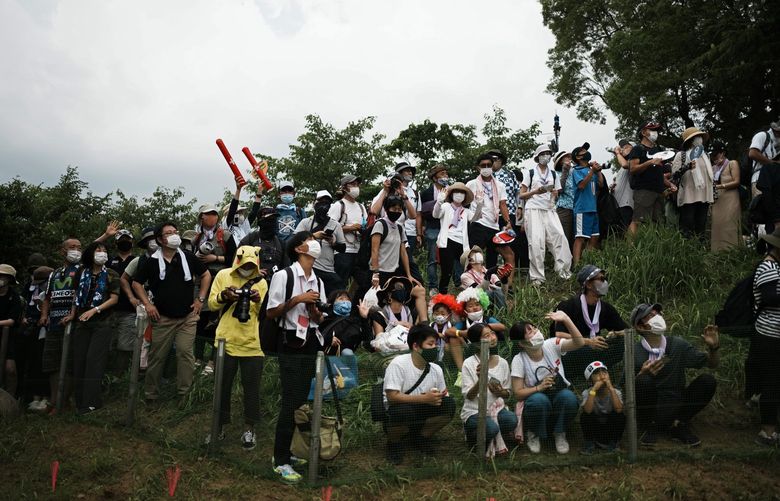 Masked fans watch from a hillside during the men’s cross country mountain bike competition at the 2020 Summer Olympics, Monday, July 26, 2021, in Izu, Japan. (AP Photo/Thibault Camus) OLYGH311 OLYGH311