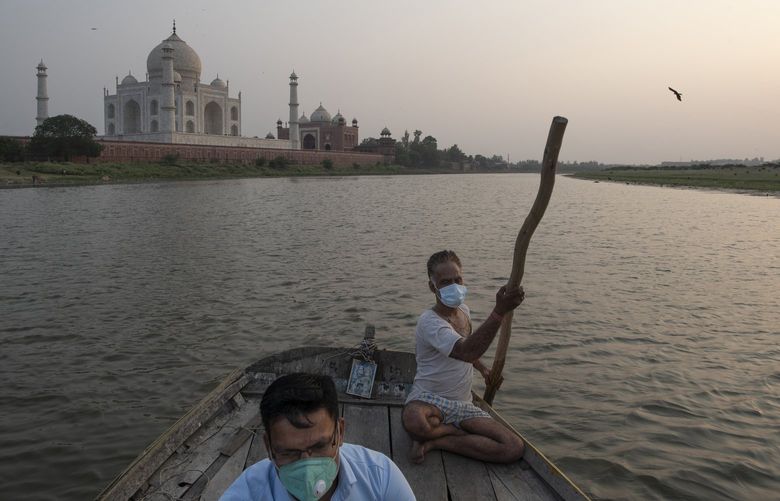 Sumit Chaurasia, left, a guide at the Taj Mahal, in front of the monument in Agra, India, June 23, 2021, while on the Yamuna river. While the Taj Mahal partially reopened in mid-June — with strict limits on the number of visitors — Chaurasia’s life, like much of India, remains in limbo: no longer totally shut down, but far from fully normal or safe. (Saumya Khandelwal/The New York Times)