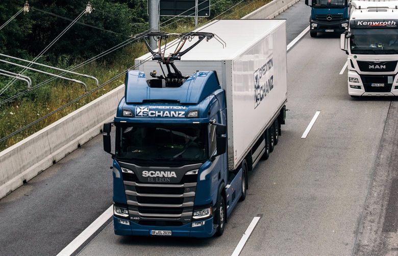 A truck draws electric power from overhead wires as it is driven along a highway near Erzhausen, Germany, on July 9, 2021. The system is energy efficient because it delivers power directly from the electrical grid to a truck’s motors.  (Felix Schmitt/The New York Times)