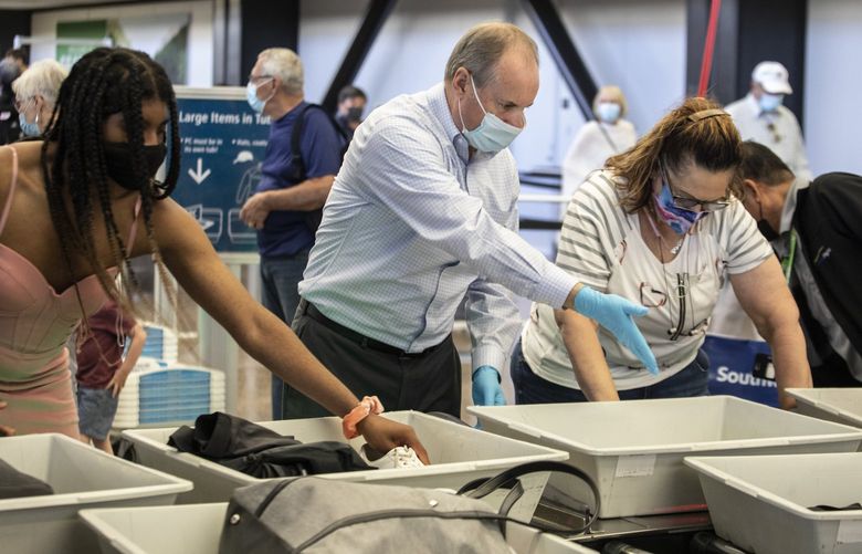Monday, July 26, 2021.   TSA Federal Security Director Jeff Holmgren, center,  helps with customer service at the automated screening lane at Sea-Tac airport before travelers go through security.   217725