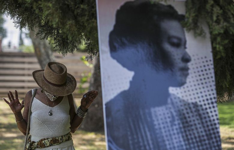 Zenobia Millet, left, standing next to the photo of anti-slavery and civil rights activist Ellen Garrison Clark offers her respect at a ceremony held to unveil headstone for the unmarked grave of Clark at Mountain View Cemetery on Saturday, June 19, 2021, in Altadena, California. (Irfan Khan/Los Angeles Times/TNS)