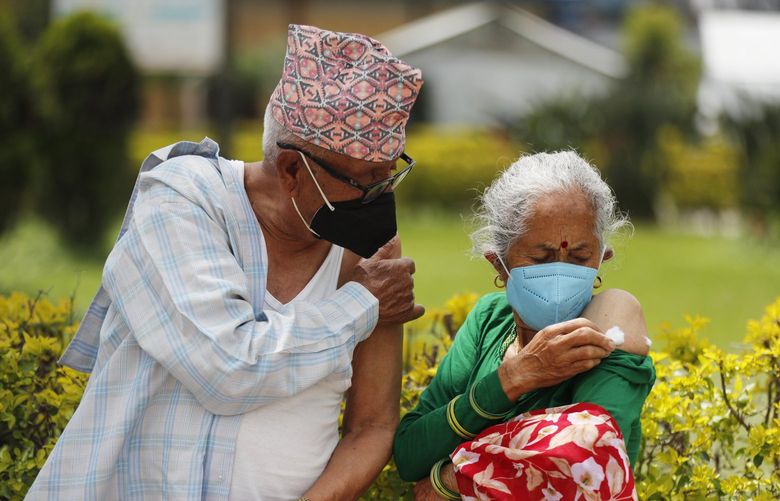 An elderly Nepalese couple hold their arms after receiving AstraZeneca COVID-19 vaccine in Kathmandu, Nepal, Monday, Aug. 9, 2021. (AP Photo/Niranjan Shrestha) XNS102 XNS102