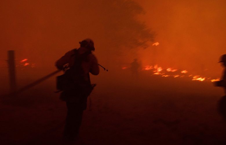 A firefighter works a fire line of the Dixie Fire on Diamond Mountain Road near Taylorsville, Calif. on Monday night, Aug. 9, 2021. Over the weekend the Dixie fire burned through enough of the Sierra Nevada to become the second largest fire in California’s history. (Christian Monterrosa/The New York Times) XNYT5
