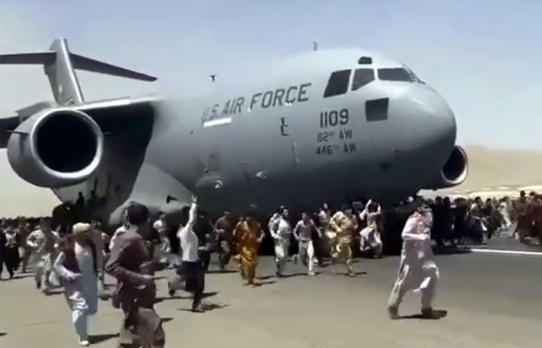 Hundreds of people run alongside a U.S. Air Force C-17 transport plane as it moves down a runway of the international airport, in Kabul, Afghanistan, Monday, Aug.16. 2021. Thousands of Afghans have rushed onto the tarmac at the airport, some so desperate to escape the Taliban capture of their country that they held onto the American military jet as it took off and plunged to death. (Verified UGC via AP) AFG102 AFG102