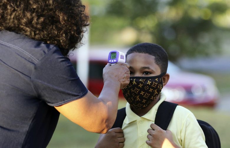 FILE – In this Monday, Aug. 24, 2020, file photo, fifth-grader Marcques Haley, gets his temperature checked by school nurse Rachel White before entering Stephens Elementary School in Little Rock, Ark. Most Arkansas public school students will be required to wear masks when 2001 classes begin in mid-August 2021, following moves by dozens of districts in response to a judge blocking the state’s mask mandate ban. (Tommy Metthe/The Arkansas Democrat-Gazette via AP, File) ARLID701 ARLID701