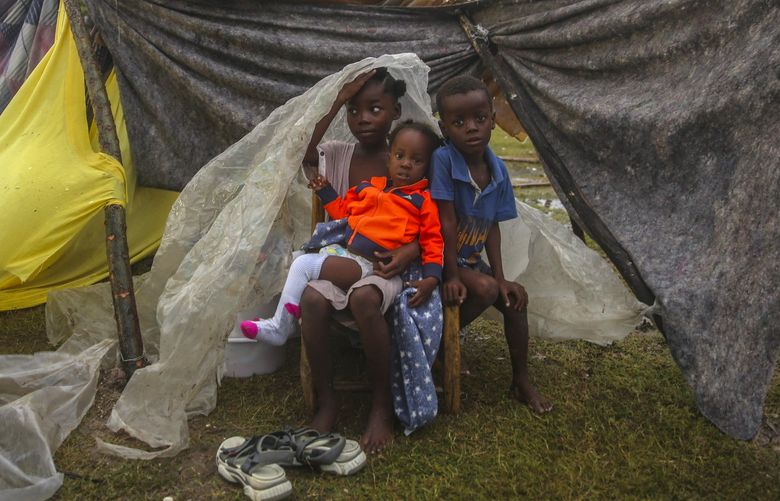 Earthquake-displaced children huddle under a piece of plastic the morning after Tropical Storm Grace swept over Les Cayes, Haiti, Tuesday, Aug. 17, 2021, three days after a 7.2-magnitude earthquake. (AP Photo/Joseph Odelyn) XRE101 XRE101