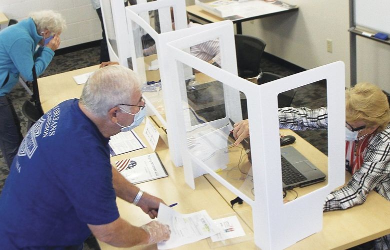 Poll workers at Pellissippi State Community College wear face masks and stay separated from voters by plastic barriers during early voting in Blount County, Tenn. on Wednesday, Oct. 14, 2020.  (Tom Sherlin/The Daily Times via AP) TNMAR101