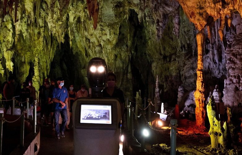 Persephone guides the visitors inside Alistrati cave, about 135 kilometers (84 miles) northeast of Thessaloniki, Greece, Monday, Aug. 2, 2021. Persephone, billed as the world’s first robot used as a tour guide inside a cave, has been welcoming visitors to the Alistrati cave, since mid-July. (AP Photo/Giannis Papanikos) XTS407 XTS407