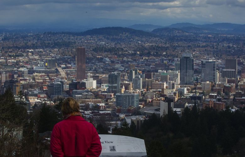 A woman checks out the view of Portland, Oregon from the Pittock Mansion, looking towards (in foreground)  the Pearl District and downtown Portland. Shot Thursday, February 23, 2017.