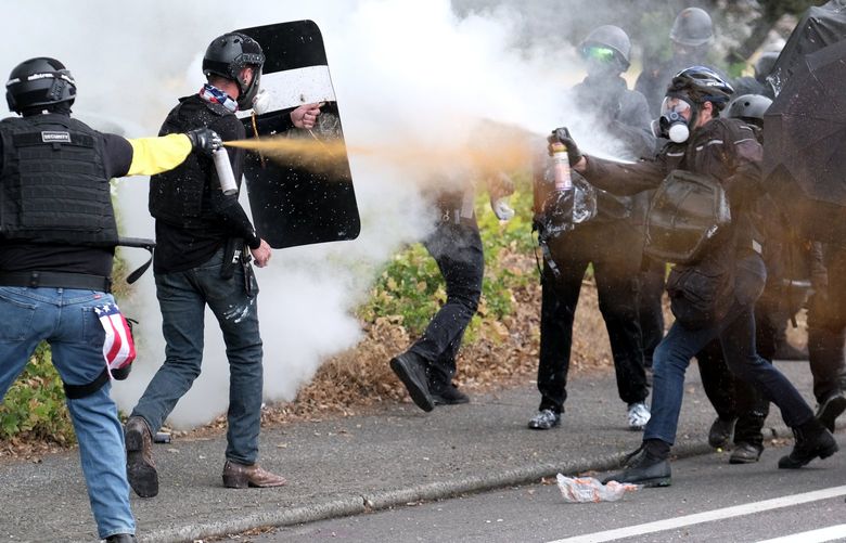 Members of the far-right group Proud Boys and anti-fascist protesters spray bear mace at each other during clashes between the politically opposed groups on Sunday, Aug. 22, 2021, in Portland, Ore. (AP Photo/Alex Milan Tracy) ORAT114 ORAT114