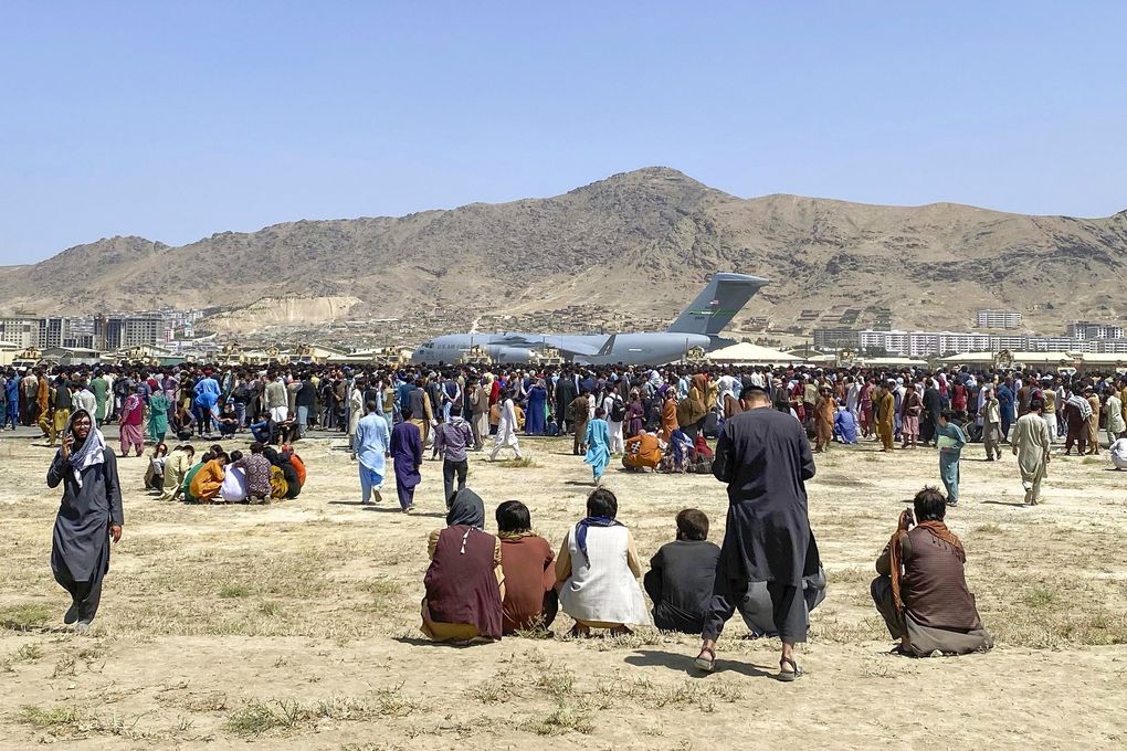 Hundreds of people gather near a U.S. Air Force C-17 transport plane at a perimeter of the international airport in Kabul on Aug. 16. (Shekib Rahmani / AP)