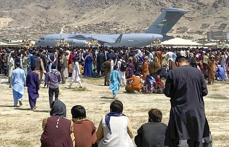 Hundreds of people gather near a U.S. Air Force C-17 transport plane at a perimeter at the international airport in Kabul, Afghanistan, Monday, Aug. 16, 2021. On Monday, the U.S. military and officials focus was on Kabul’s airport, where thousands of Afghans trapped by the sudden Taliban takeover rushed the tarmac and clung to U.S. military planes deployed to fly out staffers of the U.S. Embassy, which shut down Sunday, and others. (AP Photo/Shekib Rahmani) XRG116