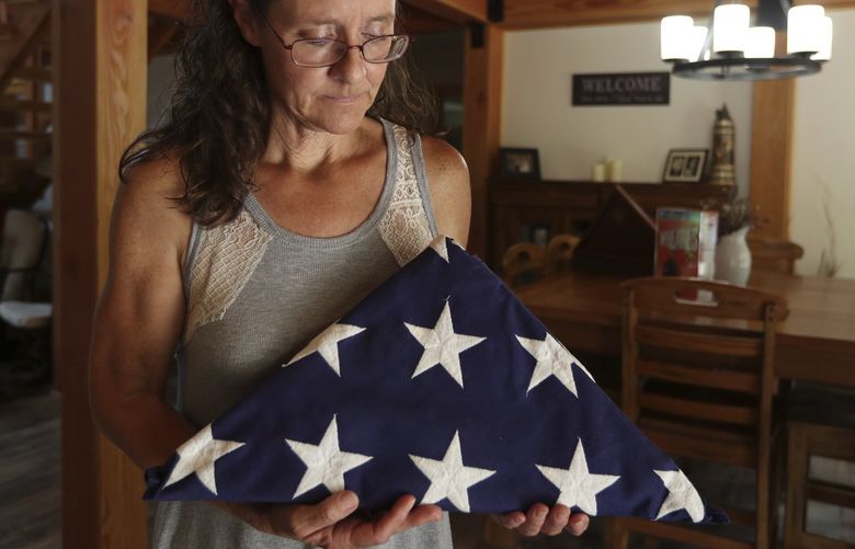 Gretchen Catherwood holds the flag that draped the casket of her son, Marine Lance Cpl. Alec Catherwood, in Springville, Tenn., on Wednesday, Aug. 18, 2021. In 2010, Alec, 19, was killed in Afghanistan fighting the Taliban. When he was alive, she loved to touch his face. He had baby soft skin and when she put her hands on his cheeks, this big tough Marine felt like her little boy. (AP Photo/Karen Pulfer Focht) NY604 NY604