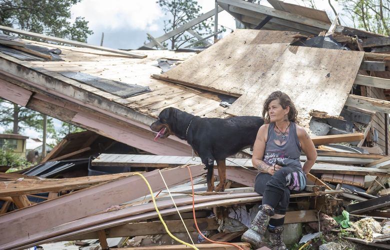 Fran Tribe and her dog Dave sit outside a home destroyed by Hurricane Ida in Houma, La., Monday, Aug. 30, 2021. (Scott Clause/The Daily Advertiser via AP) LALAF206 LALAF206