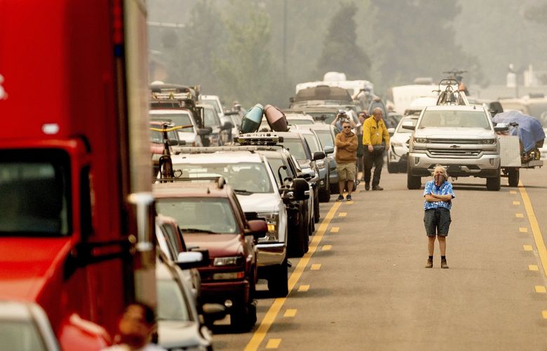 With the Caldor Fire approaching, Dawn Svymbersky stands in the middle of Highway 50 as evacuee traffic stands still in South Lake Tahoe, Calif., on Monday, Aug. 30, 2021. (AP Photo/Noah Berger) CANB109 CANB109