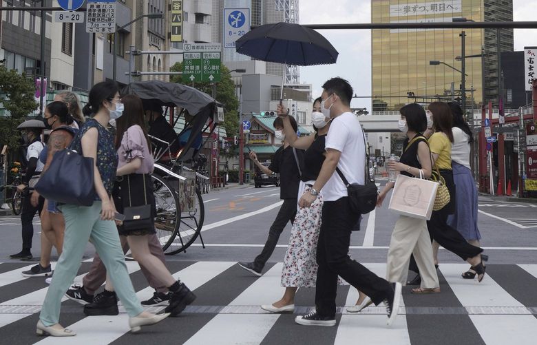People walk along a pedestrian crossing in the tourist district of Asakusa, near the landmark Tokyo Skytree tower in Tokyo, Japan on Saturday, July 31, 2021. (AP Photo/Kantaro Komiya)