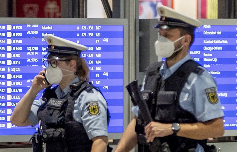 German police officers wearing face mask walk past a flight board in a terminal at the airport in Frankfurt, Germany, Tuesday, May 11, 2021. Flight numbers went down after the outspread of the corona virus. (AP Photo/Michael Probst)