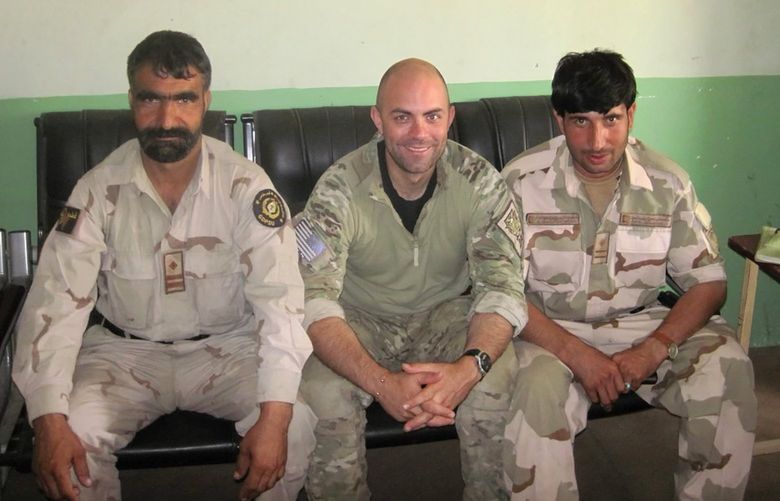 In this undated photo provided by Ryan Brummond, U.S. Special Forces Officer Ryan Brummond, center, is seated next to Mohammad Khalid Wardak, right, in Afghanistan. Khalid, as he’s called by his friends, had no intention of leaving Afghanistan, where he was a high-profile national police officer who’d worked alongside American special forces to defeat the Taliban. Then with stunning speed, his government collapsed. Now he is in hiding with his wife and four children, wounded and hunted by the Taliban, desperately hoping that American officials will repay his loyalty by helping his family escape almost certain death. (Ryan Brummond via AP) NYCD801 NYCD801