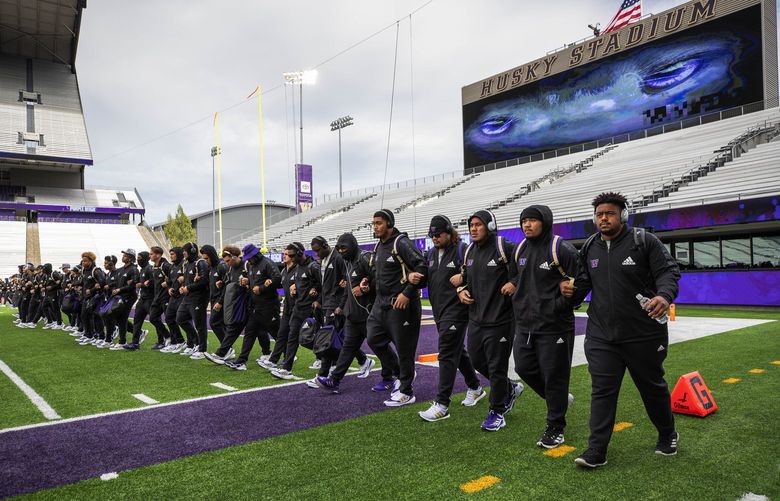 Washington links arms and walks to midfield as they arrive for Saturday’s game with Montan.
.
The University of Montana Grizzlies played the Washington Huskies in NCAA Football Saturday, September 4, 2021 at Husky Stadium, in Seattle, WA. 218136