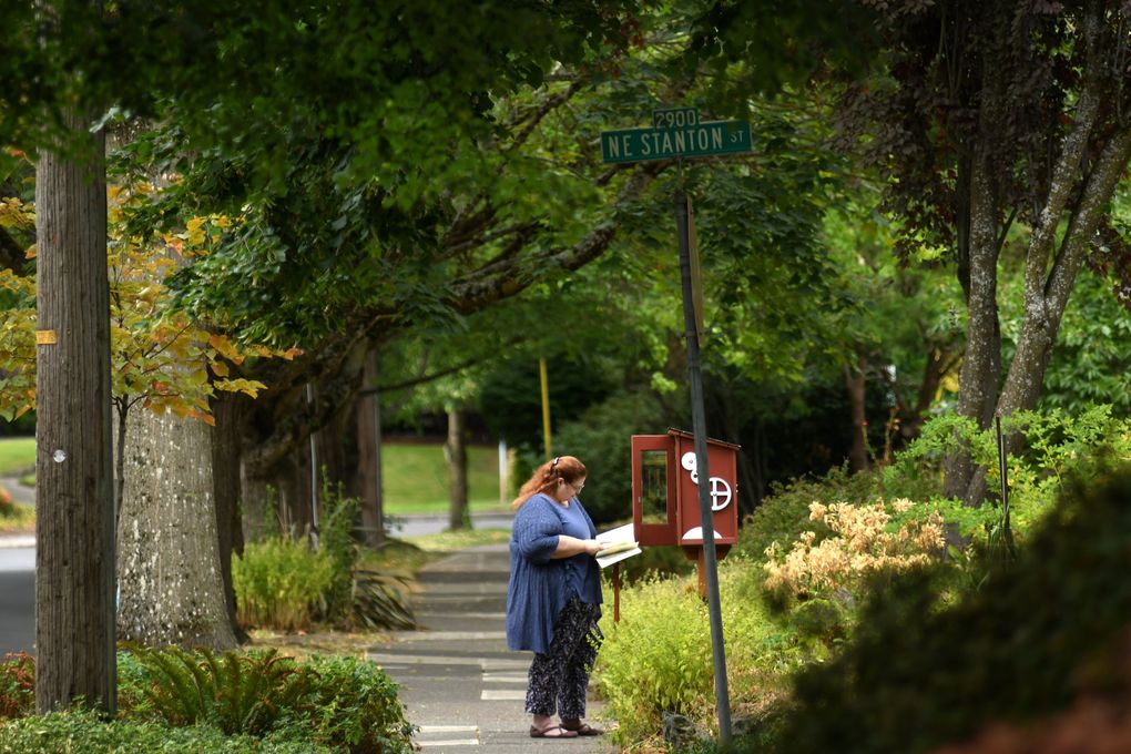 Elizabeth Van Iersel, of Portland, examines a Little Free Library on Northeast 37th Avenue, on the same block as Cleary’s childhood home. Van Iersel drives around the neighborhood stocking the Little Free Libraries with children’s books. (JiaYing Grygiel / The Seattle Times)
