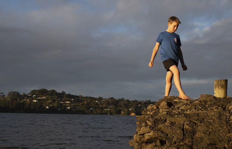 Jago Haag, 9, plays at the water’s edge at sunset, in Auckland Saturday, Sept. 4, 2021. The southern winter that just ended in New Zealand was the warmest ever recorded, and scientists say that climate change is driving temperatures ever higher. (Sylvie Whinray/New Zealand Herald via AP) NZH801 NZH801