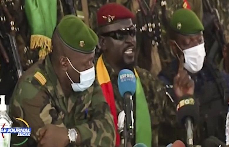 In this image made from video, Junta leader Col. Mamady Doumbouya, center, wearing a red beret and sunglasses, addresses officials in the capital Conakry, Guinea Monday, Sept. 6, 2021. Guinea’s new military leaders sought to tighten their grip on power Monday after overthrowing President Alpha Conde, ordering the soldiers from his presidential guard to now join the junta forces and barring government officials from leaving the country. (Radio Television Guineenne via AP) NAI816 NAI816
