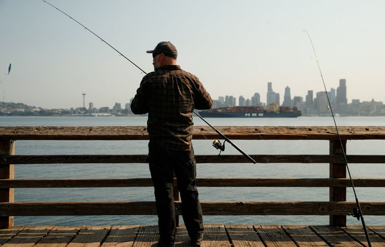 Jason Williams fishes for chinook salmon in West Seattle Monday, August 2, 2021. Smoke from the wildfires in Oregon and California is expected to be in the atmosphere in Seattle this week.   217801
