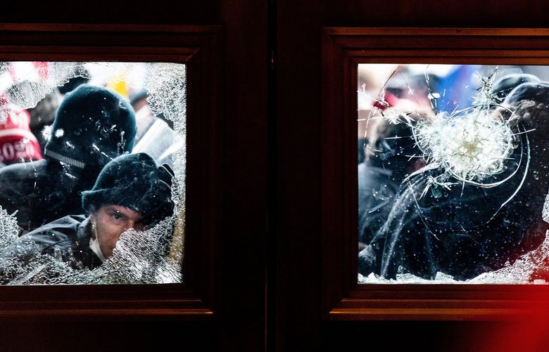 FILE — Rioters breaking through a glass window on a door to the Capitol in Washington on Jan. 6, 2021. A married couple from Virginia who illegally entered the Capitol on Jan. 6 with a protest sign questioning coronavirus vaccines pleaded guilty on Monday, June 14, to a misdemeanor charge of disorderly conduct, becoming the first two people charged with minor crimes to accept responsibility for their role in the assault on the building that day. (Erin Schaff/The New York Times) XNYT118
