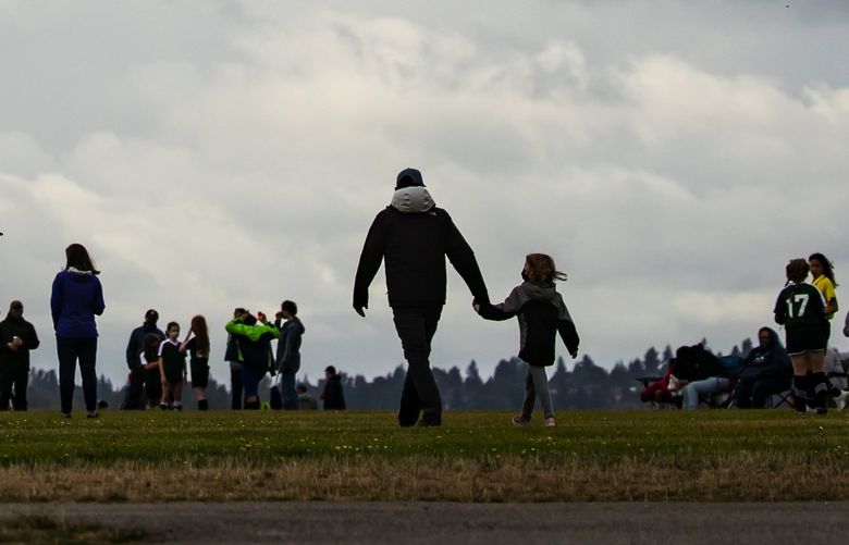 Parents and kids attend a girlsâ€™ soccer match against a backdrop of dramatic clouds, at Jefferson Park in the Beacon Hill neighborhood of Seattle Sunday September 19, 2021.