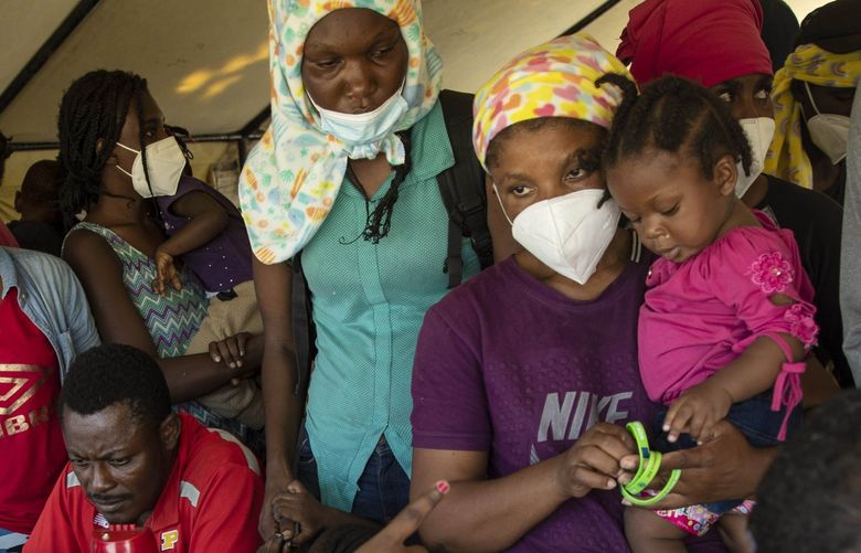 Haitians who were deported from the U.S. border with Mexico are attended by members of the IOM UN Migration organization before they get tested for COVID-19 at Toussaint Louverture International Airport in Port-au-Prince, Haiti, Monday, Sept. 20, 2021. The U.S. is flying Haitians camped in a Texas border town back to their homeland. (AP Photo/Rodrigo Abd) ABD105 ABD105