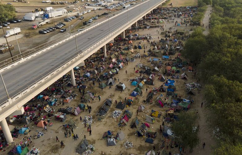 Migrants, many from Haiti, are seen at an encampment along the Del Rio International Bridge near the Rio Grande, Tuesday, Sept. 21, 2021, in Del Rio, Texas.  The options remaining for thousands of Haitian migrants straddling the Mexico-Texas border are narrowing as the United States government ramps up to an expected six expulsion flights to Haiti and Mexico began busing some away from the border.  (AP Photo/Julio Cortez) TXJC105 TXJC105