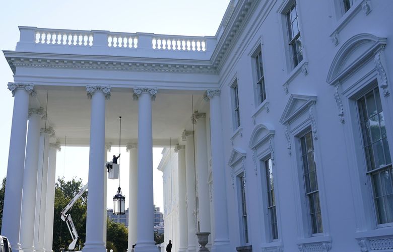 A worker works on the light fixture over the North Portico of the White House in Washington, Friday, Sept. 3, 2021. (AP Photo/Susan Walsh) DCSW105 DCSW105