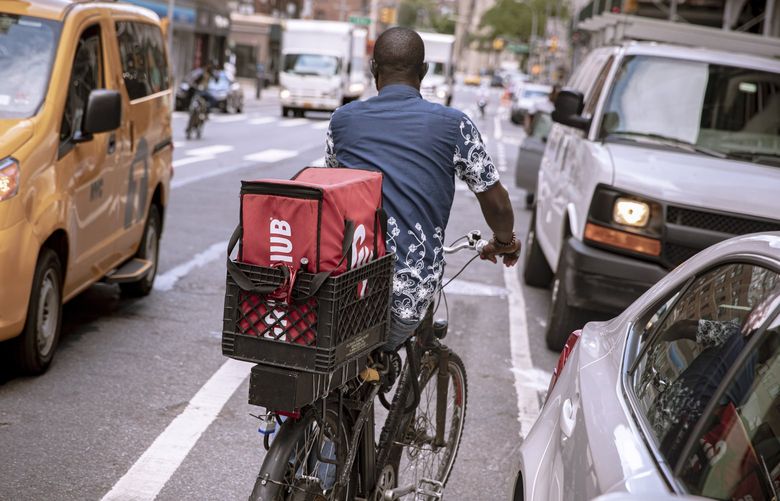 FILE — A delivery worker bikes through Manhattan, July 13, 2020. The New York City Council is on track to pass a groundbreaking package of legislation on Sept. 23, 2021, that will set minimum pay and improve working conditions for couriers employed by app-based food delivery services like Grubhub, DoorDash and UberEats. (Amr Alfiky/The New York Times) XNYT46 XNYT46