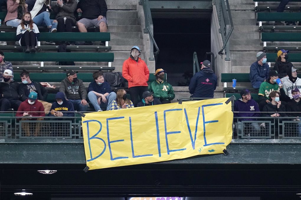 A “Believe” sign, similar to one seen in the TV series “Ted Lasso,” hangs from outfield seats as fans look on during a baseball game between the Seattle Mariners and Oakland Athletics Monday, Sept. 27, 2021, in Seattle. (Elaine Thompson / AP)