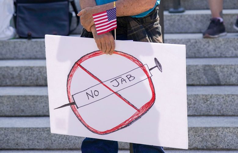 A sign that reads “No Jab” is held by a person taking part in a demonstration opposing mask and COVID-19 vaccine mandates outside the Legislative Building, Wednesday, Aug. 18, 2021, at the Capitol in Olympia, Wash. Washington Gov. Jay Inslee announced Wednesday that Washington state is expanding its vaccine mandate to include all public, charter and private school teachers and staff, as well as those working at the state’s colleges and universities. Inslee also expanded the statewide indoor mask mandate in place for non-vaccinated individuals to include those who are vaccinated. (AP Photo/Ted S. Warren) WATW109