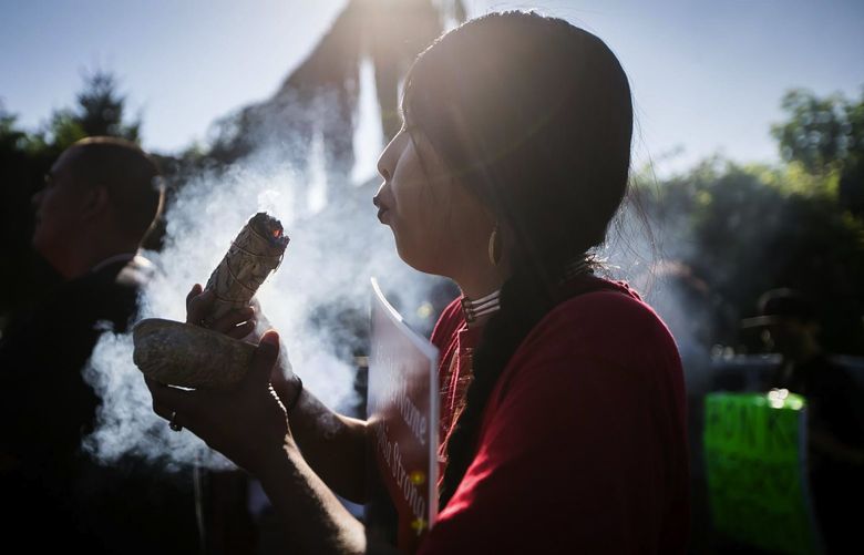 Gabrielle Colfax burns sage during a prayer walk dedicated to missing and murdered Indigenous people Wednesday, July 14, 2021, on South Camas Avenue in Wapato, Wash.