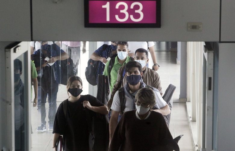 Passengers deplane at Tocumen International Airport in Panama City, Monday, Oct. 12, 2020. Panama is lifting a broad spectrum of COVID-19 pandemic-related restrictions on Monday, including re-opening international flights and allowing hotels, casinos, and tourism-related activities. (AP Photo/Arnulfo Franco)