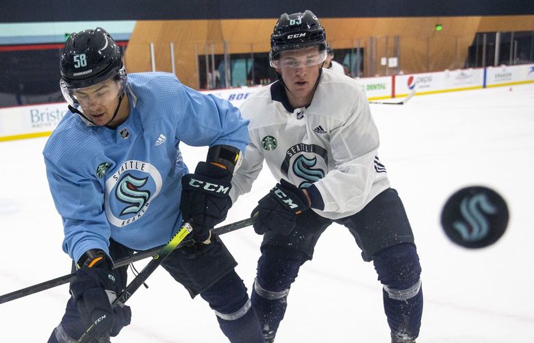 Seattle Kraken players Alexander True (11), Connor Carrick (58) and Jacob Melanson (63) fight for the puck as it flies upward in a drill during training camp at Kraken Community Iceplex on Thursday, Sept. 23, 2021.