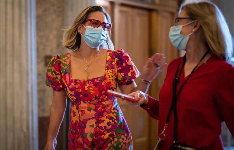 Sen. Kyrsten Sinema (D-Ariz.), left, talks with a reporter while walking to the Senate chamber for a roll call vote at the U.S. Capitol in Washington on Tuesday, Sept. 28, 2021. The centrist senator is key to the Democratic agenda in Washington. Her positions have angered some former supporters back home. (Sarahbeth Maney/The New York Times) XNYT104 XNYT104