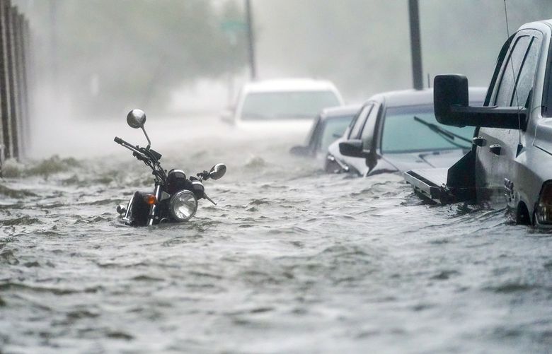 In this Sept. 16, 2020, file photo, flood waters move on the street, in Pensacola, Fla. Hurricane Sally made landfall near Gulf Shores, Alabama, as a Category 2 storm, pushing a surge of ocean water onto the coast and dumping torrential rain. This year has seen record Atlantic hurricanes and western wildfires, devastating floods in Asia and Africa and a hot, melting Arctic. It’s not just been a disastrous year, but a year of disasters. (AP Photo/Gerald Herbert, File) NYPH503