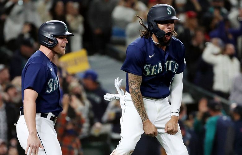 Mariners Jake Bauers, left, and J.P. Crawford celebrate at home plate after Mitch Haniger singles, which scores both, as the M’s retake the lead from the Angels in the eighth inning, Saturday, Oct. 2, 2021 in Seattle.

 218402