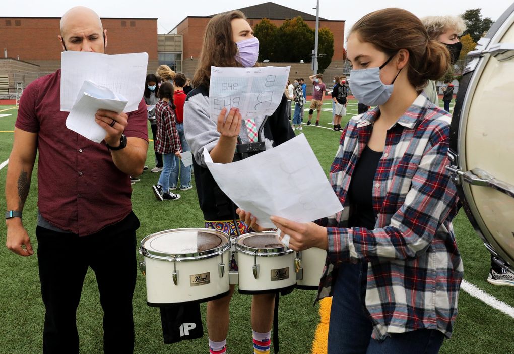 Director Jay Gillespie, Elliot Q Adamson and Anne Welman go over sheets with formations Gillespie has developed for the Ballard High marching band’s halftime performance. With 108 members at this practice, formations are complex and require precision. (Alan Berner / The Seattle Times)