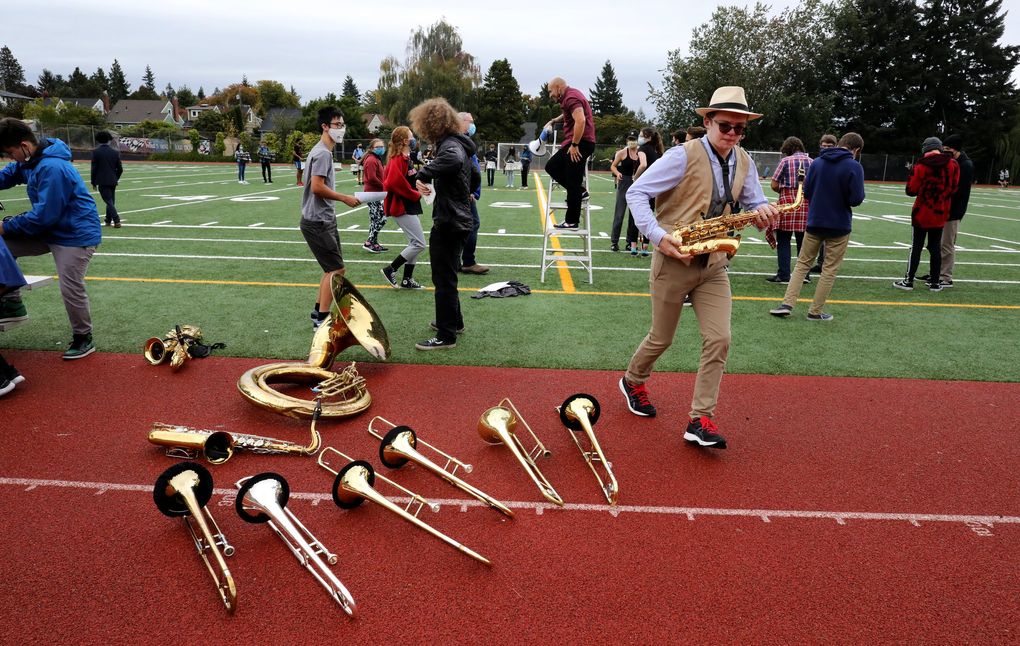 Ballard High marching band members get a brief break during a 90-minute practice after school. In the background, Jay Gillespie descends from his ladder. (Alan Berner / The Seattle Times)